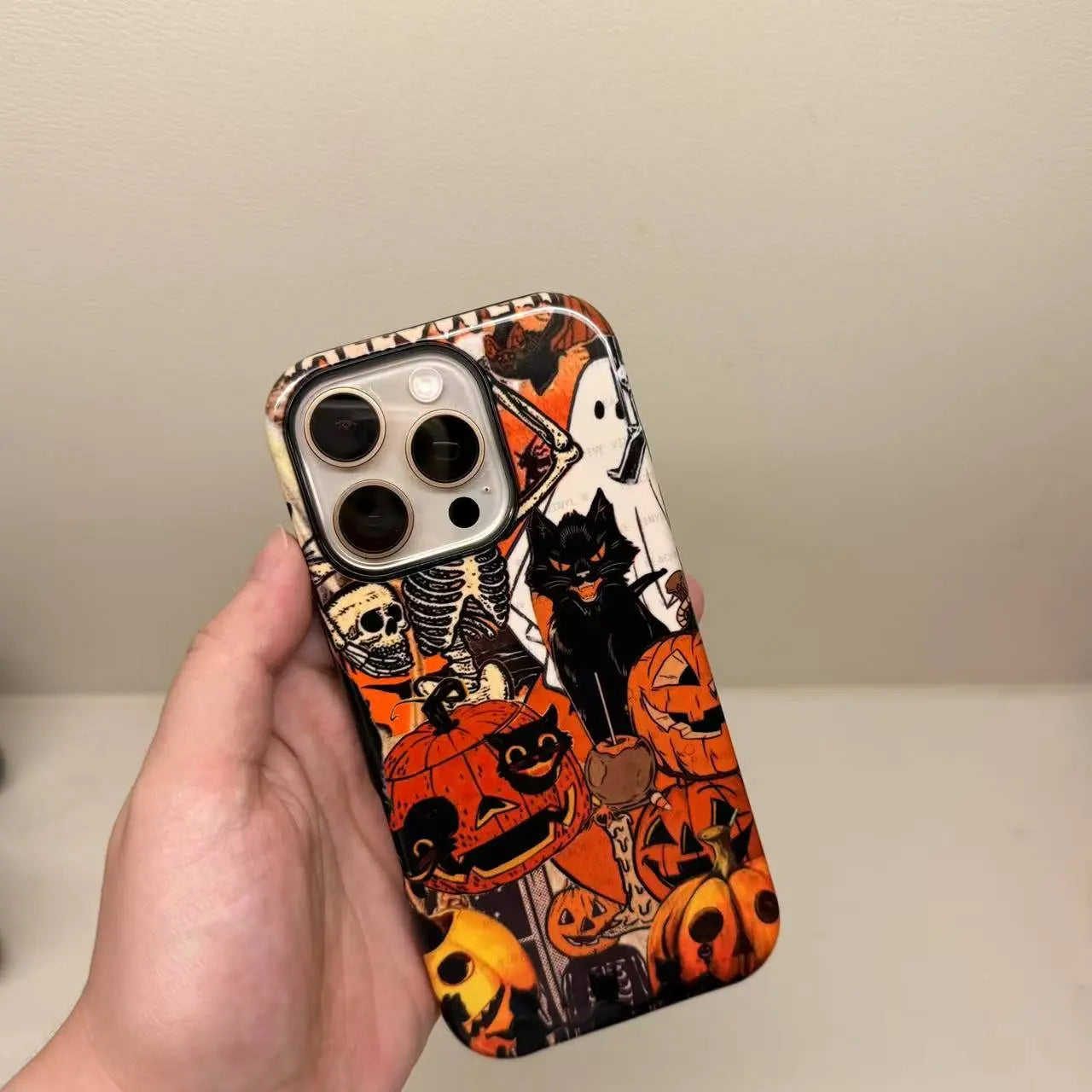 This Halloween phone case features a vintage collage of classic elements like pumpkins, black cats, and skeletons, adding a unique festive vibe.