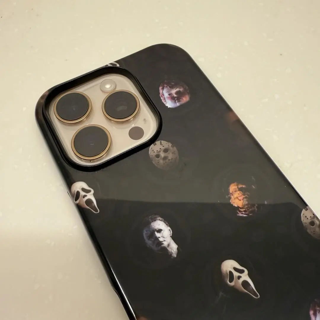 This Halloween phone case features classic horror movie character faces on a black background, offering a subtle yet mysterious vibe for your phone.