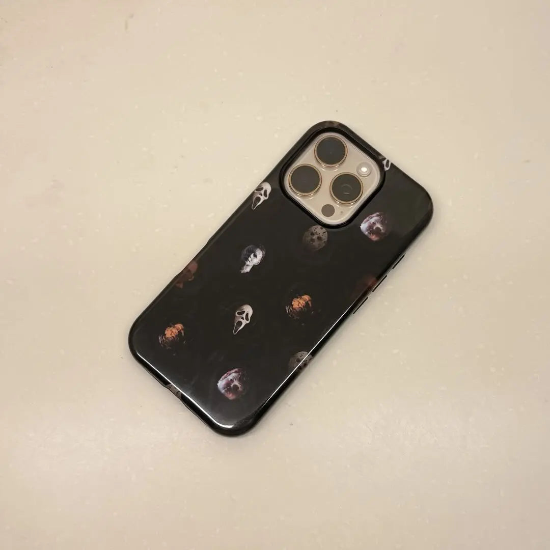 This Halloween phone case features classic horror movie character faces on a black background, offering a subtle yet mysterious vibe for your phone.