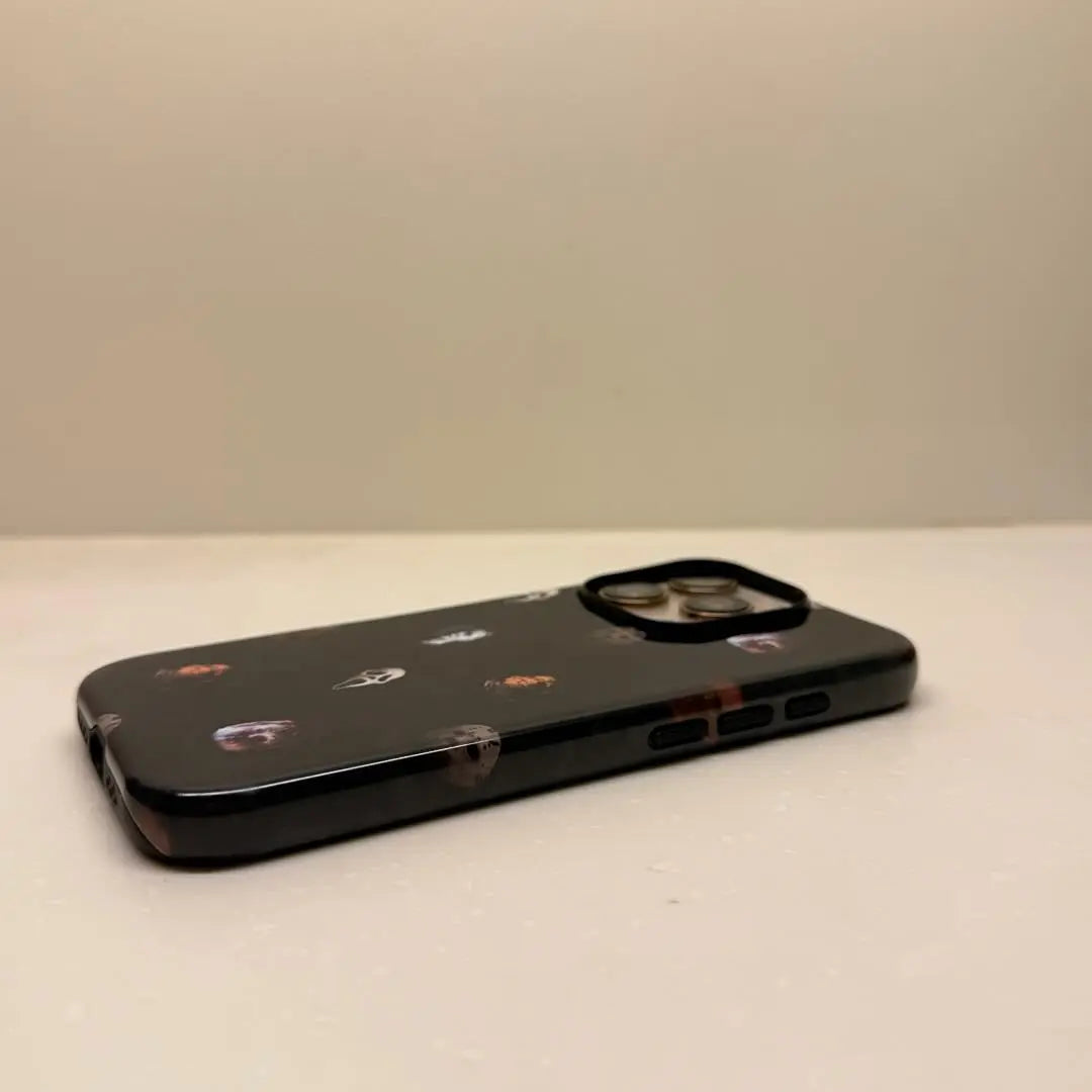 This Halloween phone case features classic horror movie character faces on a black background, offering a subtle yet mysterious vibe for your phone.
