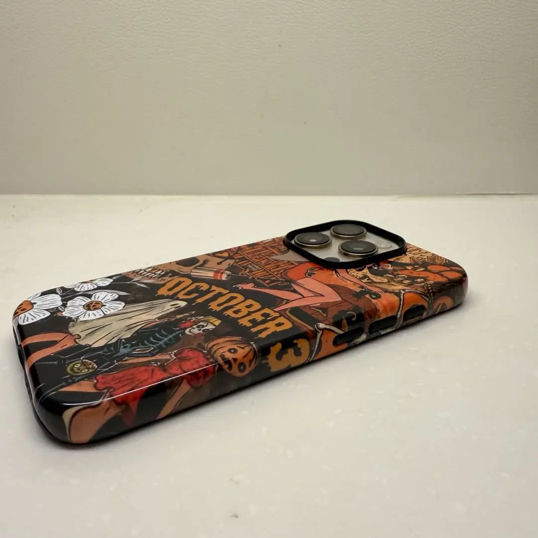 This Halloween phone case features a vintage collage of various horror elements, creating a unique and trendy accessory for the spooky season.