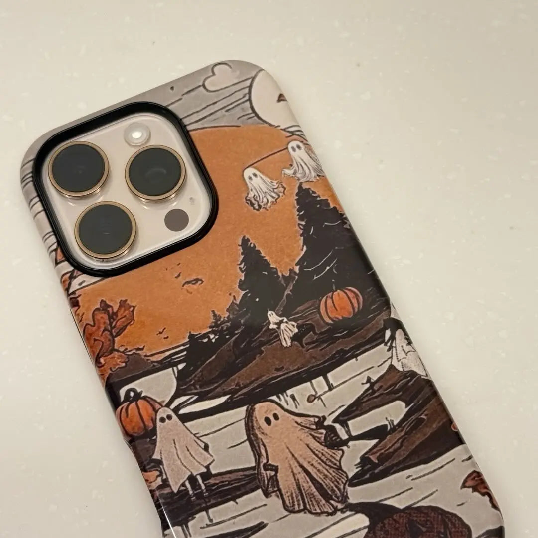 This vintage-style Halloween phone case features a charming illustration of ghosts and pumpkins, adding a unique and cozy autumn vibe to your phone.