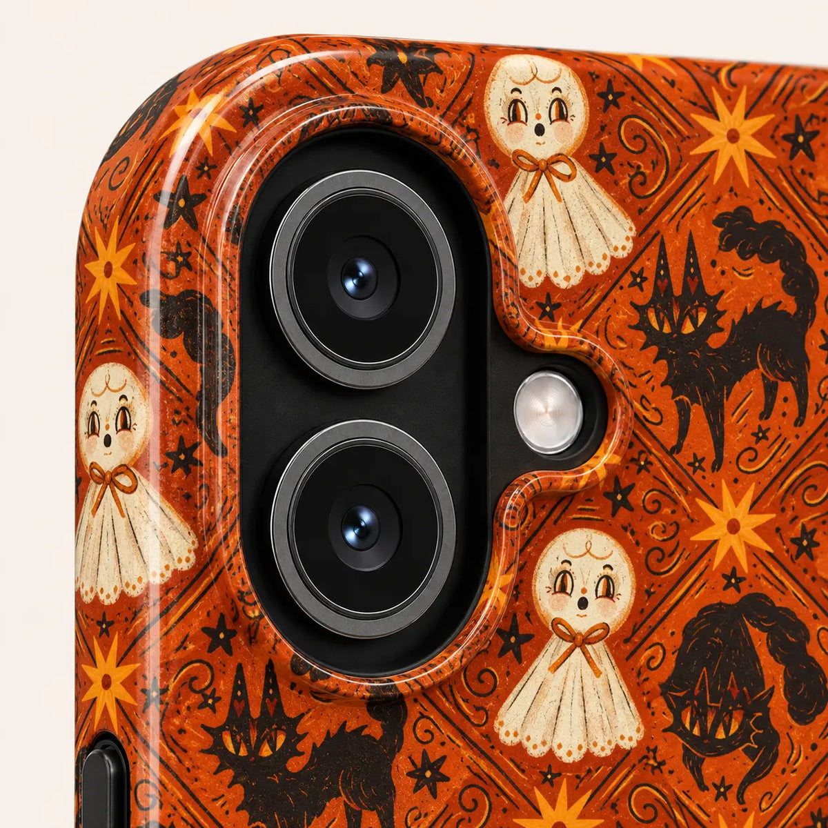 Close-up of the iPhone camera opening surrounded by orange Halloween artwork with cream ghosts, black cats and stars