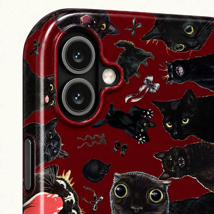 Close-up of the iPhone camera opening surrounded by expressive black cat portraits and bow illustrations on burgundy