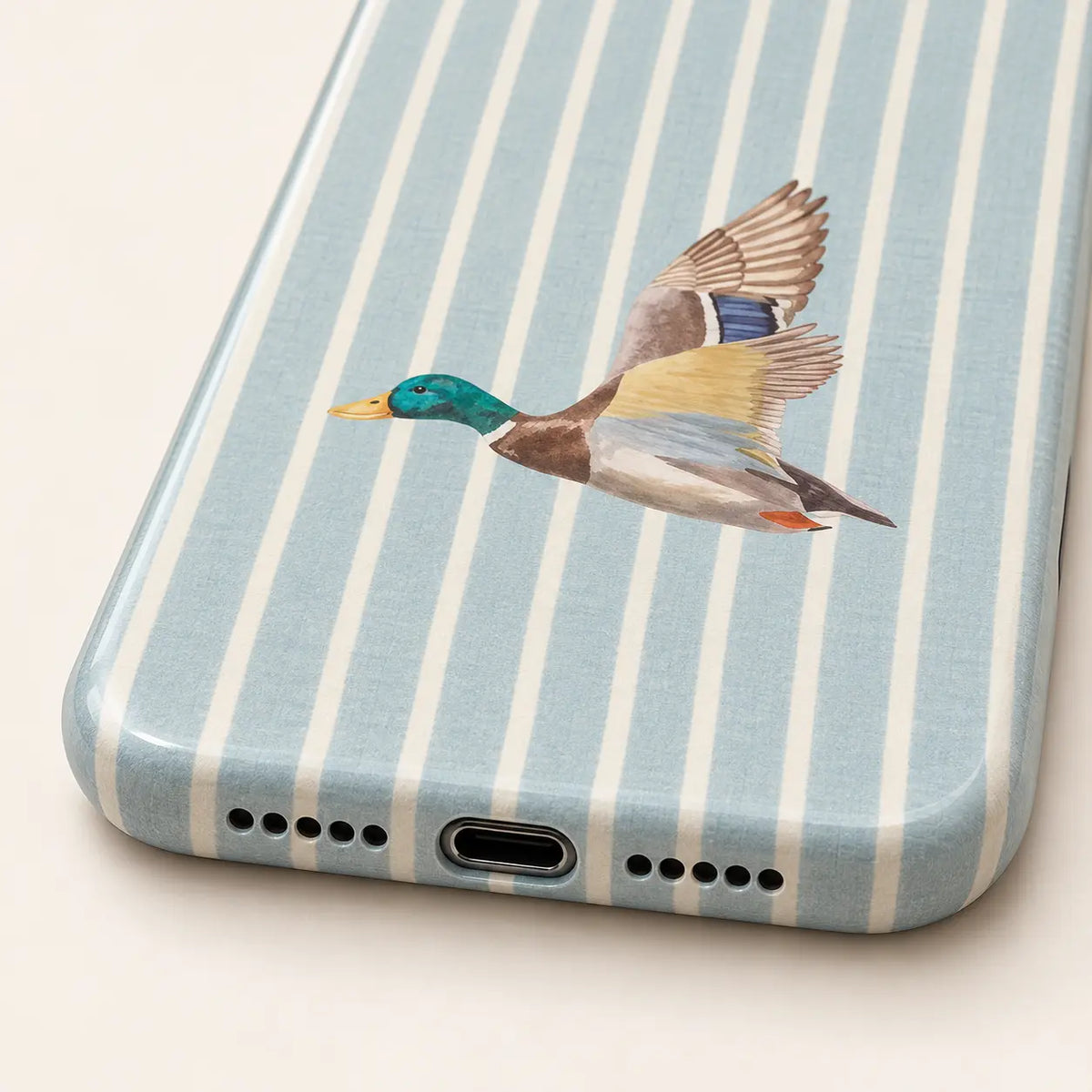 Angled iPhone side view showing continuous edge print: pale blue and cream vertical stripes; one left-facing watercolor mallard with raised wings.