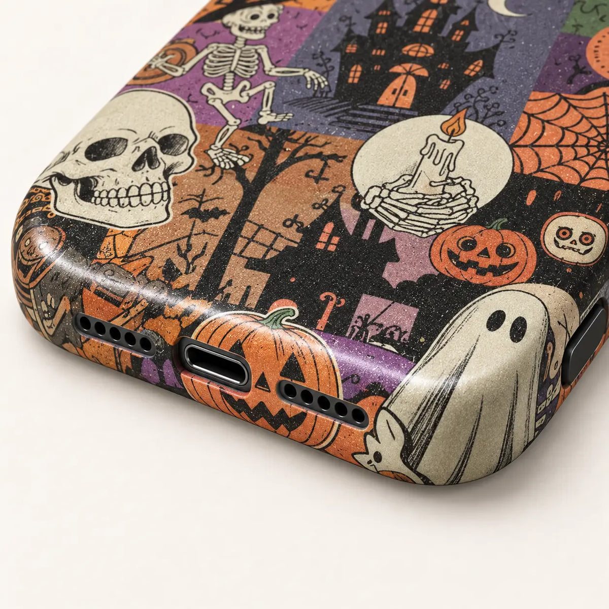 Close-up of the phone case's bottom edge and port openings, with pumpkin and ghost artwork extending around the corner