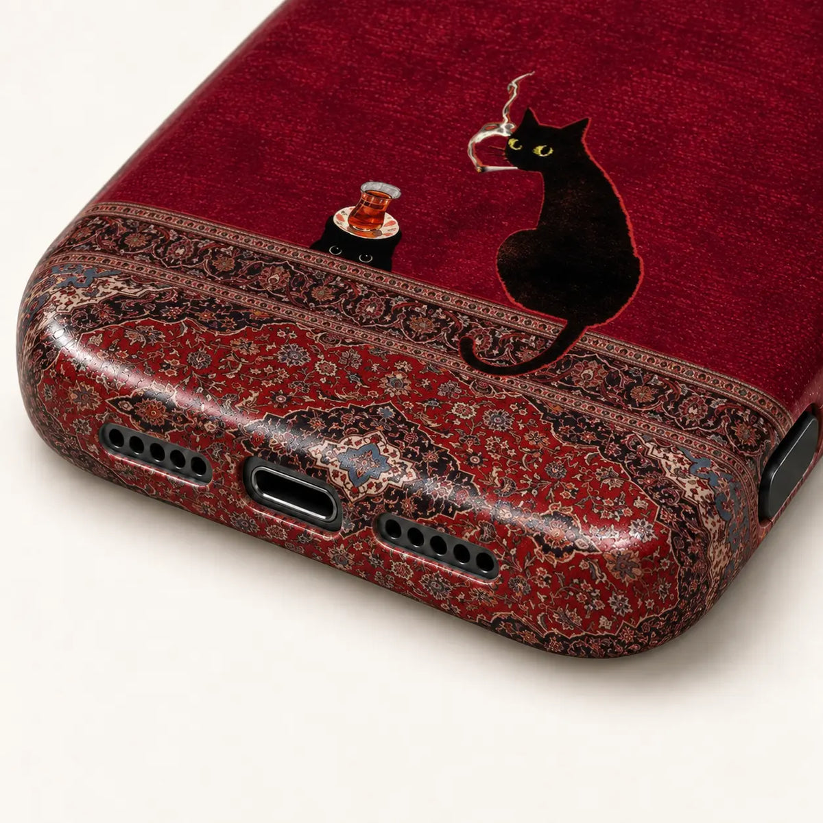 Close-up of the phone case's bottom corners and port openings, surrounded by an intricate red Persian rug pattern