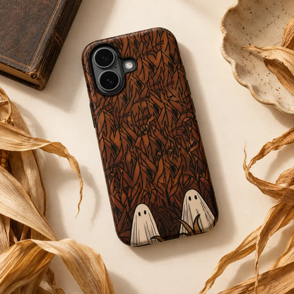 Hidden Ghosts cornfield phone case styled with dried corn leaves on a warm tabletop