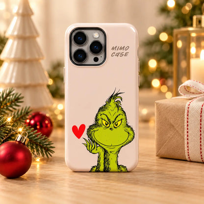 Grinch Red Heart Christmas phone case displayed in a warm festive tabletop setting