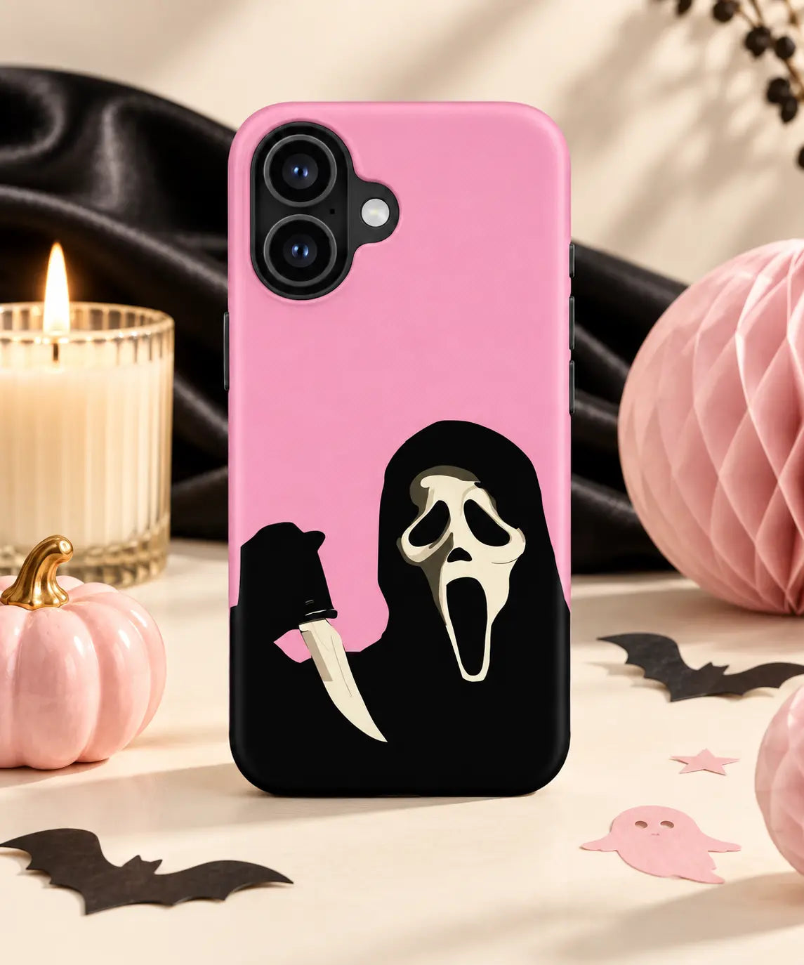 Pink scream mask phone case displayed in a stylish Halloween tabletop setting