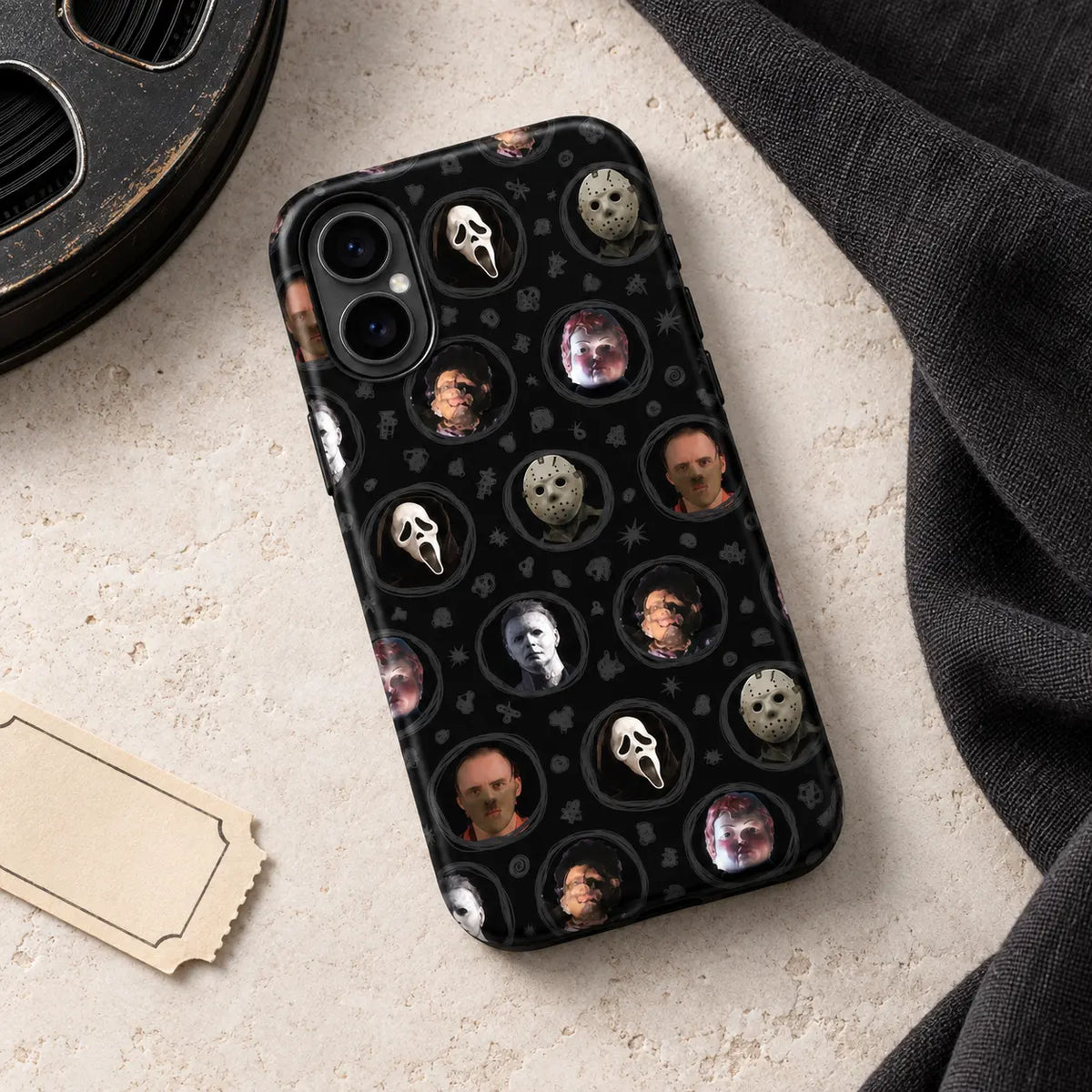 Horror movie mask portrait phone case displayed in a dark tabletop Halloween setting