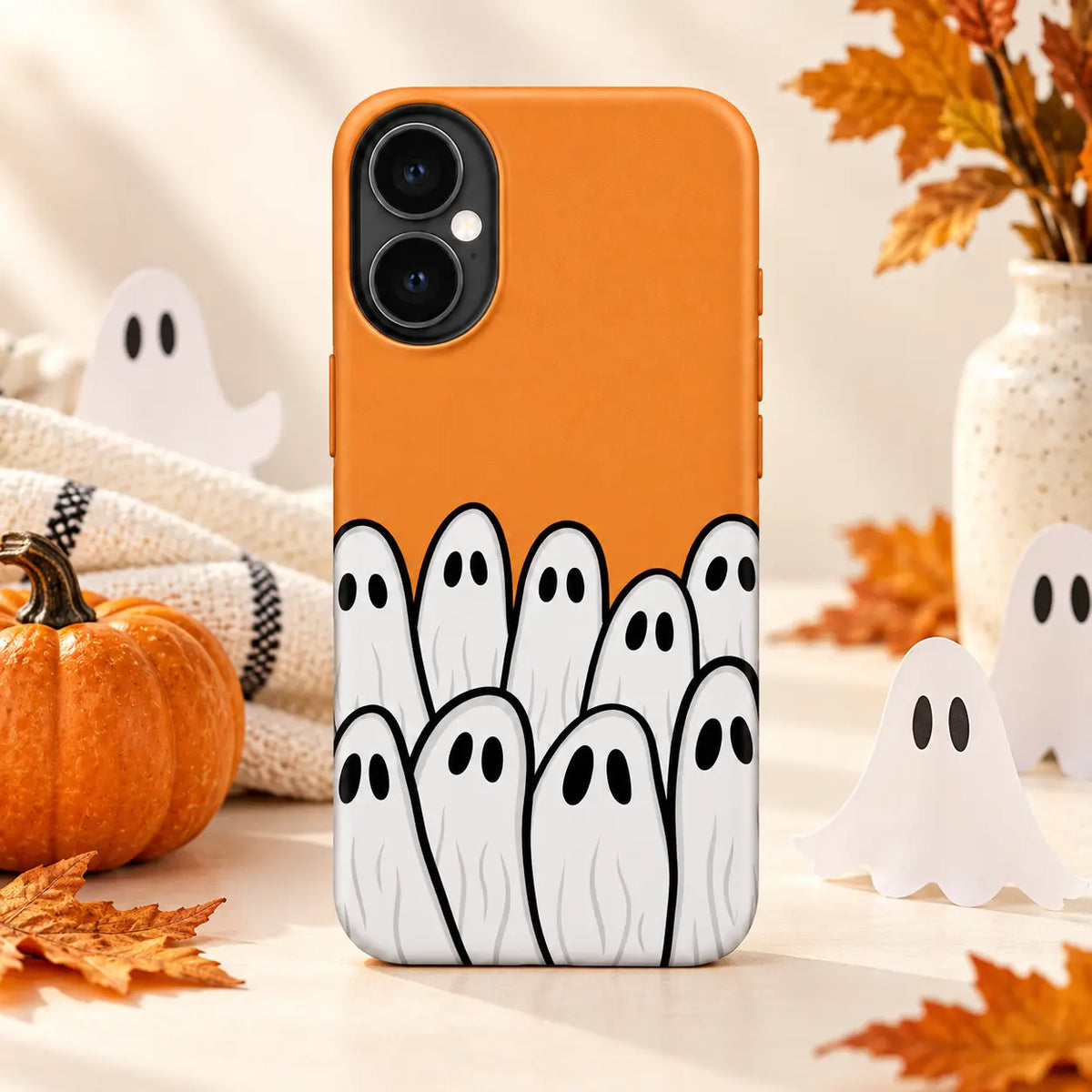 Orange ghost crowd phone case displayed in an autumn Halloween tabletop setting