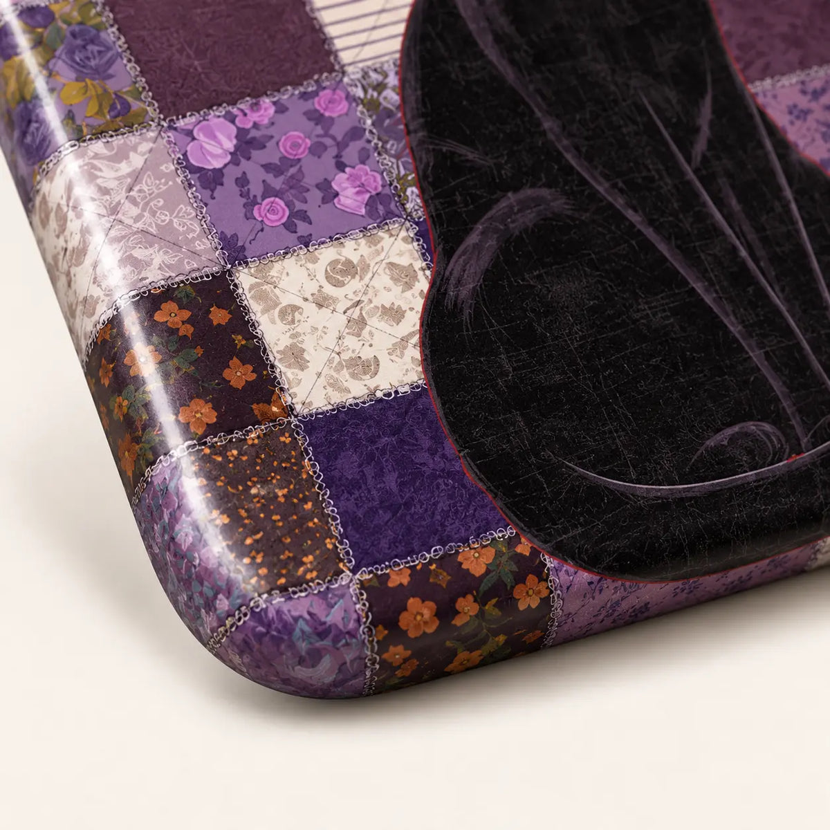 Lower curved corner detail showing the patchwork print and part of the black cat's tail.