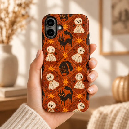 Hand holding an iPhone with an orange Halloween case featuring cream ghosts, black cats and golden starbursts