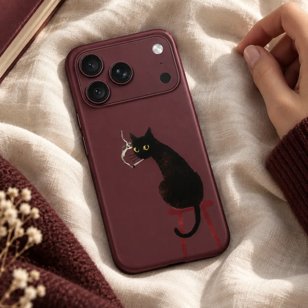 Burgundy black cat phone case displayed on ivory fabric
